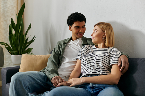 A young multicultural couple relaxes and enjoys each others company in their modern apartment.