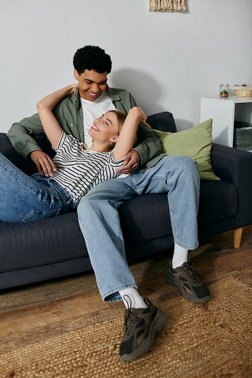 A young couple relaxes on a couch in a modern apartment, enjoying each others company.