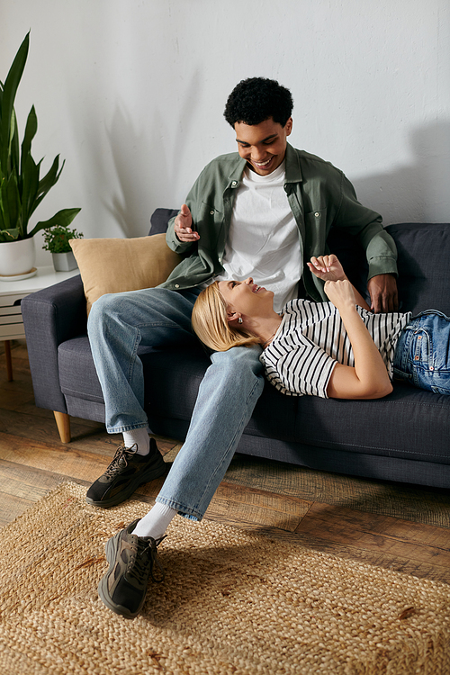 A young couple relaxes on a modern sofa in their apartment, enjoying each others company.