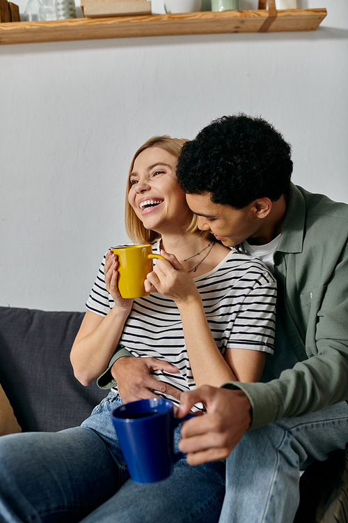 A young, multicultural couple laughs and enjoys their good morning in a modern apartment.