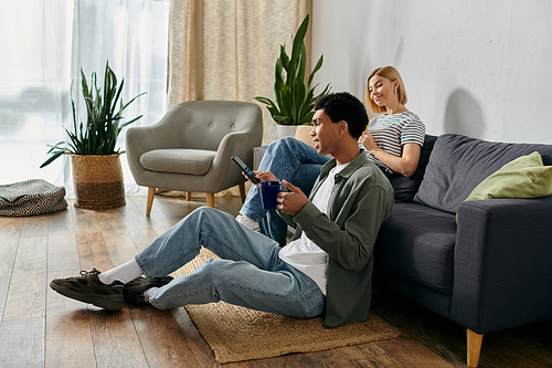 A young multicultural couple relaxes in a modern apartment, enjoying a cozy afternoon together.