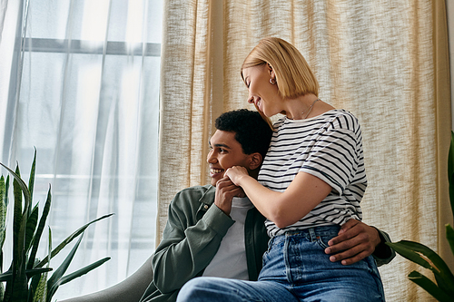 A young multicultural couple shares a tender moment in their modern apartment, enjoying the warmth of each others company.