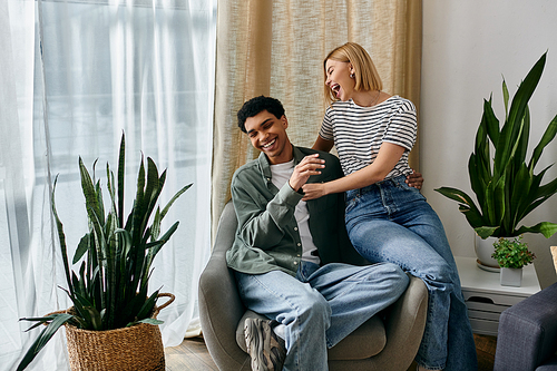 A young multicultural couple shares a laugh in a modern apartment filled with natural light and greenery.