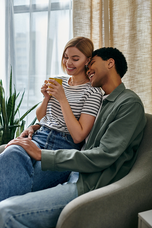 A young, multicultural couple shares a cup of coffee and a loving moment in their modern apartment.