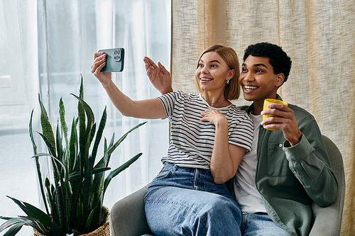 A young interracial couple smiles for a selfie while enjoying their time in a modern apartment.