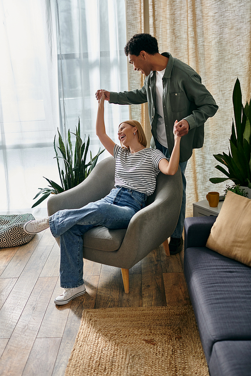 A young multicultural couple playfully interacts in their modern apartment, showcasing a lighthearted and intimate moment.