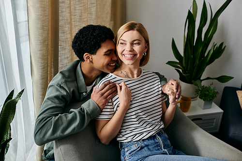 A young, multicultural couple shares a loving moment while relaxing in their modern apartment.