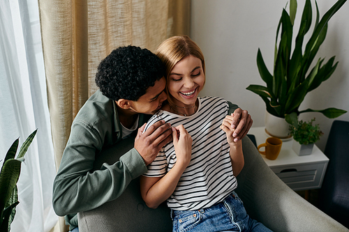 A young multicultural couple shares a tender moment in a modern apartment, filled with natural light and greenery.