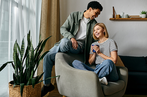 A young couple laughs and enjoys their morning coffee in their modern apartment.