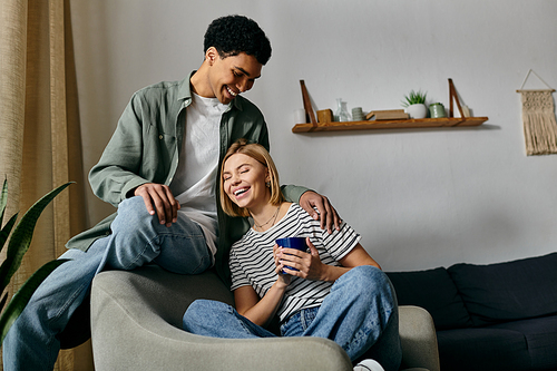 A young couple in a modern apartment shares a lighthearted moment. The woman laughs as the man smiles.