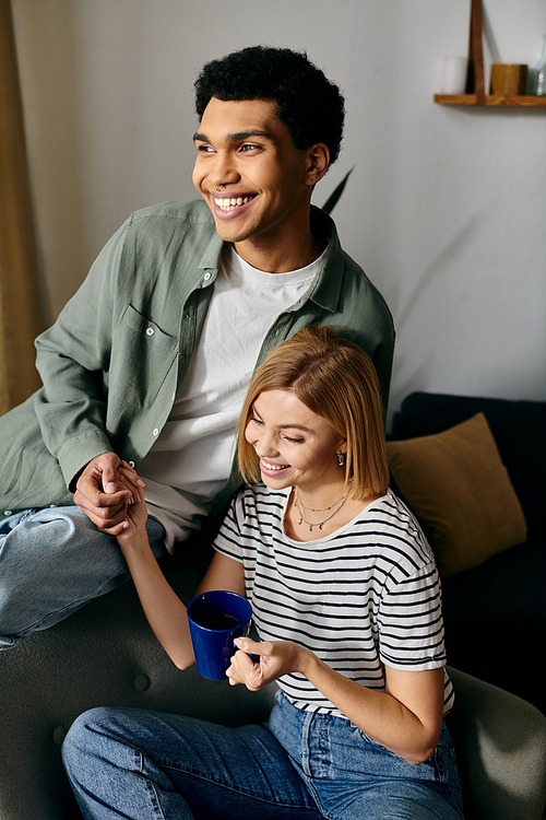 A young interracial couple smiles at each other, enjoying a relaxed afternoon in their modern apartment.