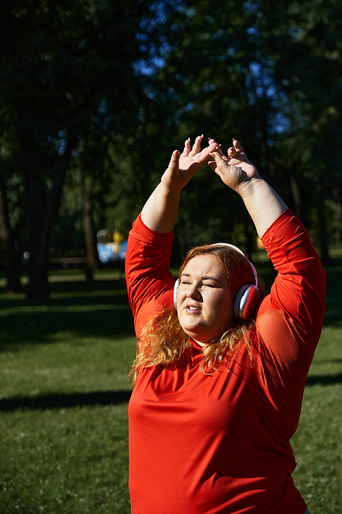 A vibrant plus size woman enjoys stretching outdoors amid nature.