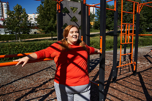 A confident woman exercises in a vibrant park under the sun.