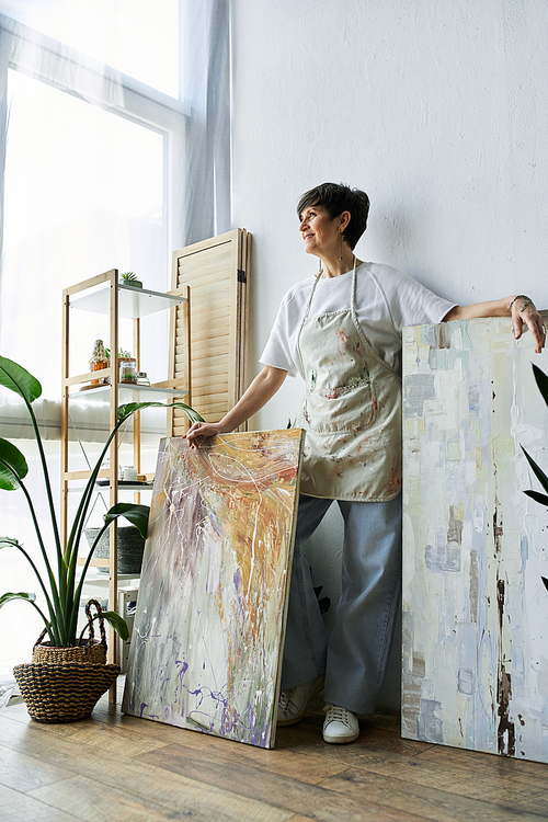 A mature woman joyfully explores her passion for painting in a bright studio.