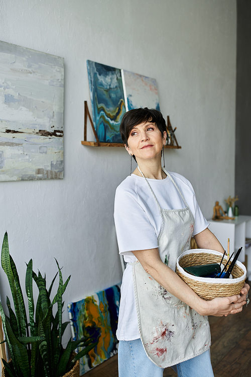 An enthusiastic painter engages with her artwork in a bright studio.