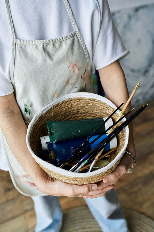 A woman enjoys her creative space while holding art materials.