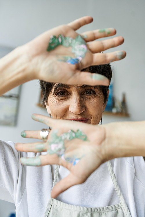 An artist reveals her paint splattered hands, celebrating her creative passion.