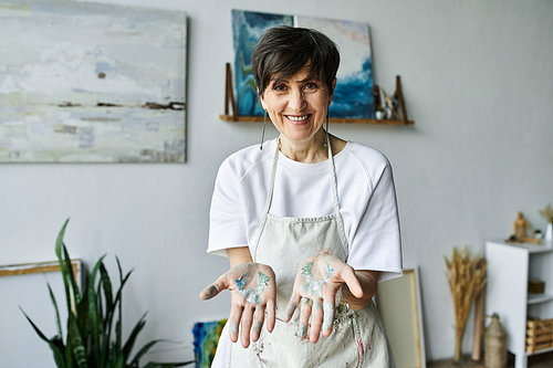 A woman shows her paint streaked hands, illustrating her passion for art.