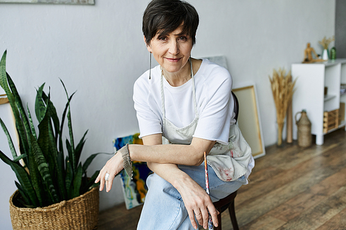 A mature woman engages in painting while surrounded by creative tools.