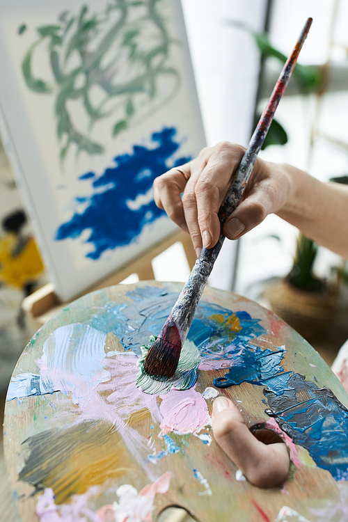 A mature woman blends colors on her palette, immersed in her artistic process.