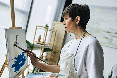 A woman focuses intently on her canvas, creating a vibrant artwork.