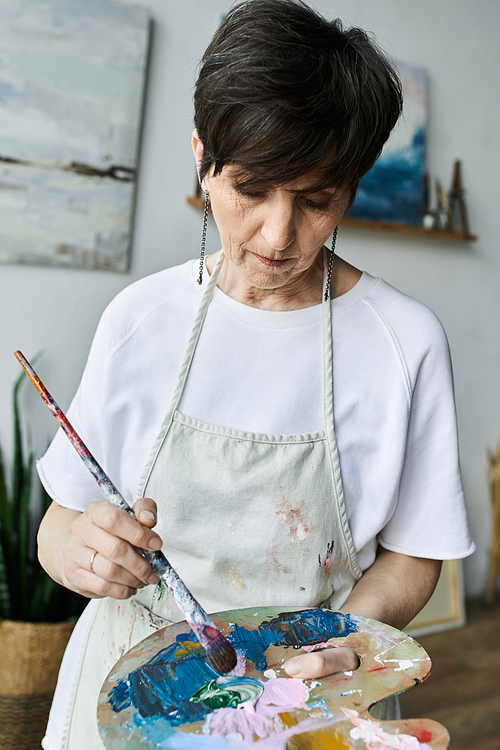 A woman passionately paints while holding a palette in her studio.