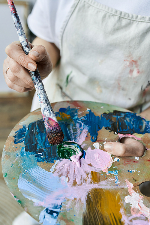 An artist blends colors on her palette, immersed in creation in her studio.