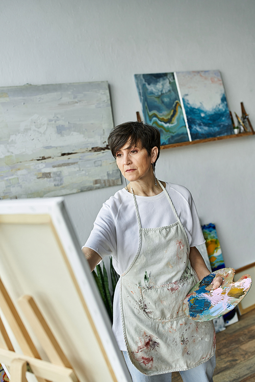 A woman engages in painting with a palette in hand, immersed in her creative space.