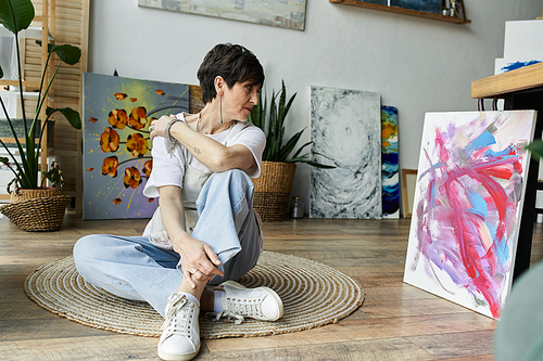 A woman deeply engaged in her painting process in a bright, inviting studio.