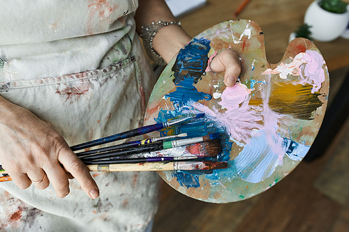 A dedicated painter mixes colors while surrounded by her artistic tools.