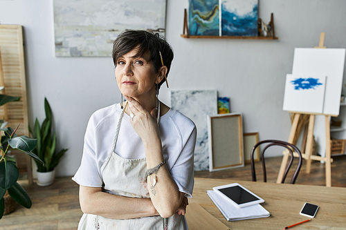 A painter thoughtfully engages with her creative space.