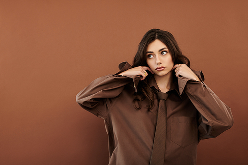 A young, beautiful woman models a chic autumn outfit in a warm studio, exuding style and confidence.