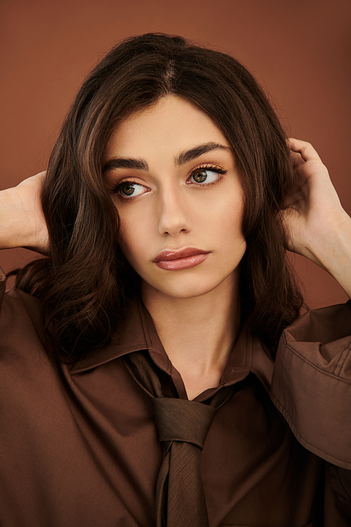 A young woman elegantly poses in a trendy autumn outfit, exuding confidence and beauty in a cozy studio ambiance.