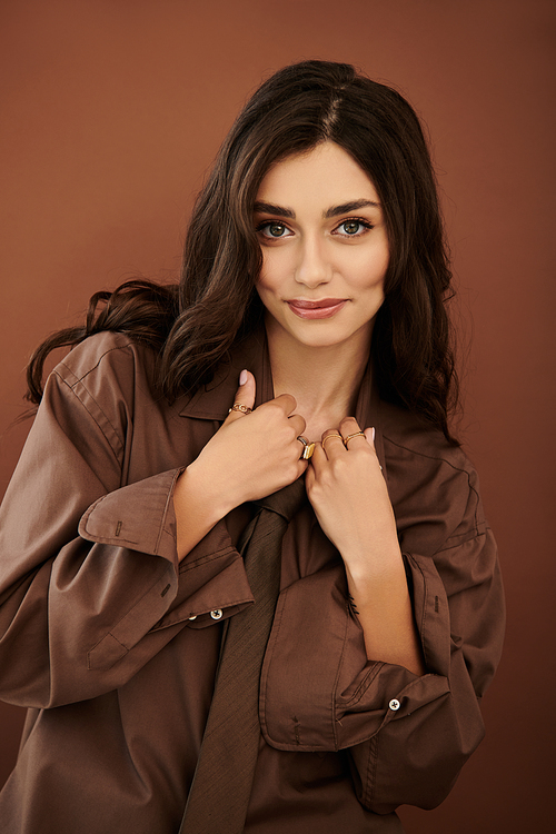 A beautiful young woman poses confidently, wearing a chic autumn outfit in a welcoming studio environment.