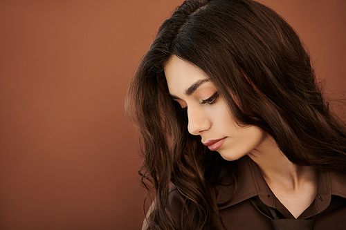 A young woman poses gracefully in a stylish autumn outfit, highlighting seasonal trends in a warm studio atmosphere.