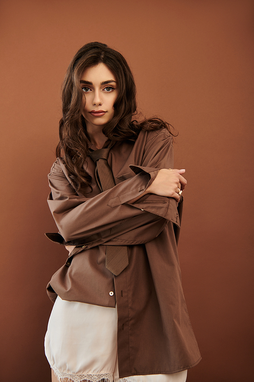 A young and beautiful woman elegantly poses in a fashionable autumn outfit, radiating warmth and style in the studio.