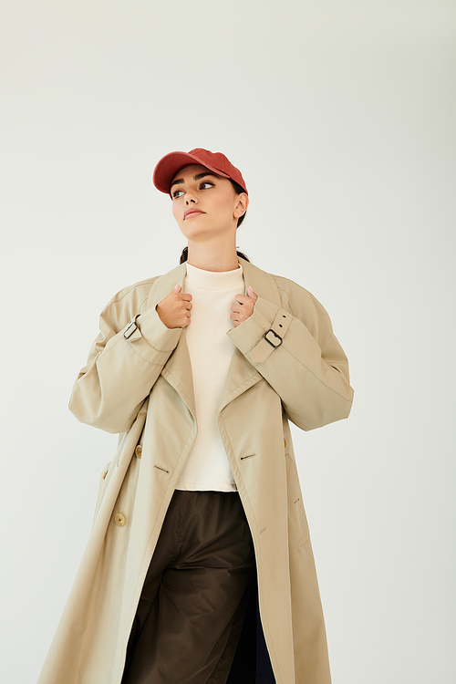 A young woman confidently poses in a fashionable autumn outfit, radiating seasonal charm and style in an elegant studio.