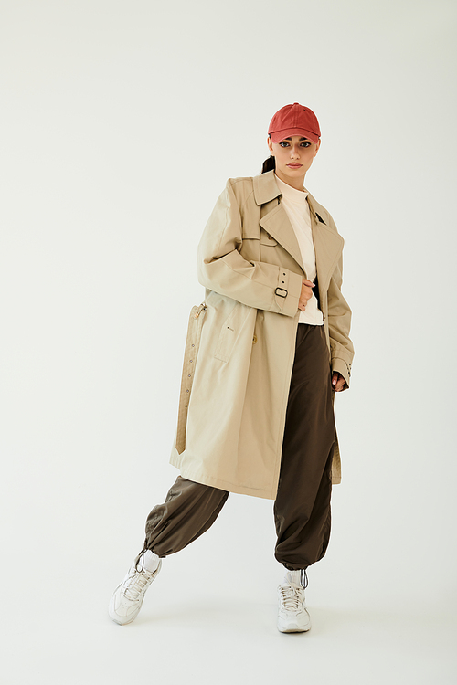 A young woman poses beautifully in a chic autumn outfit, exuding elegance in a contemporary studio atmosphere.