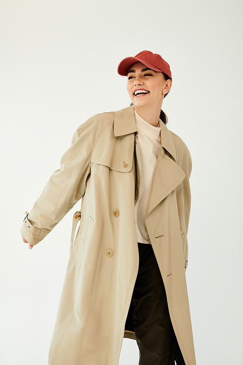 Delightful young woman exudes confidence in a chic autumn outfit, blending fashion and joy in a modern studio.