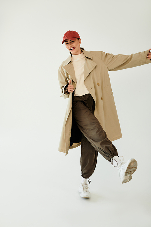 A young woman radiates confidence in a chic autumn outfit, playfully posing in a contemporary studio environment.