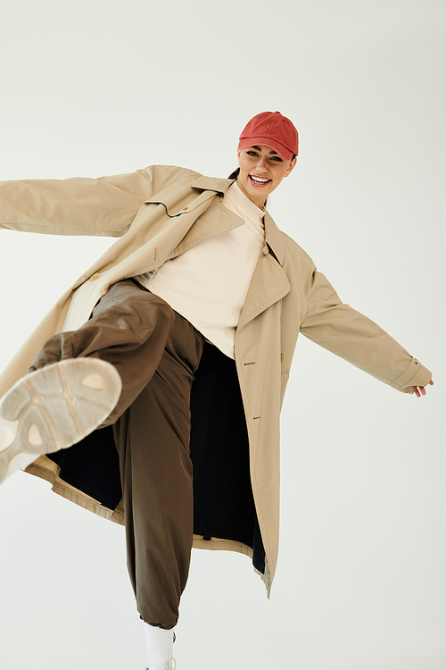 A young woman confidently poses in a trendy autumn outfit, showcasing seasonal fashion against a minimalist studio backdrop.