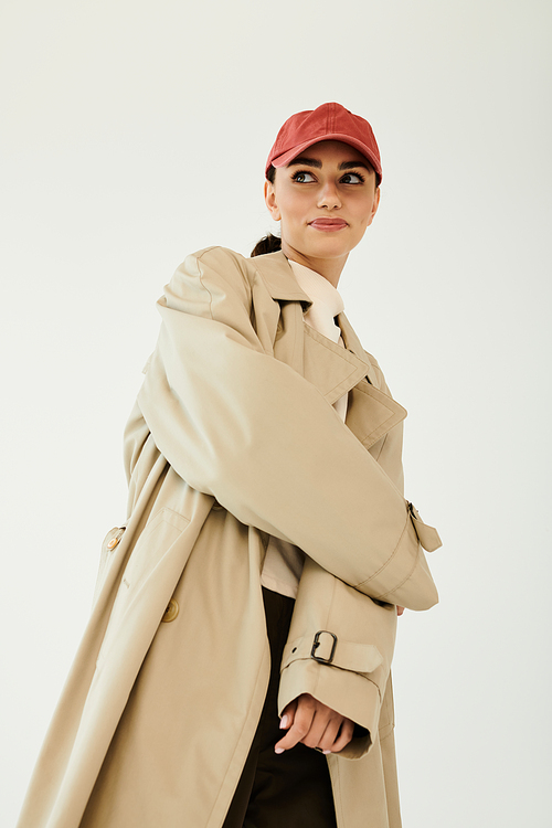 A young, beautiful woman models a trendy autumn outfit, exuding confidence in a serene studio atmosphere.