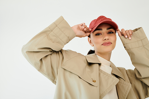 A confident young woman poses gracefully, highlighting her trendy autumn outfit in a chic studio environment.