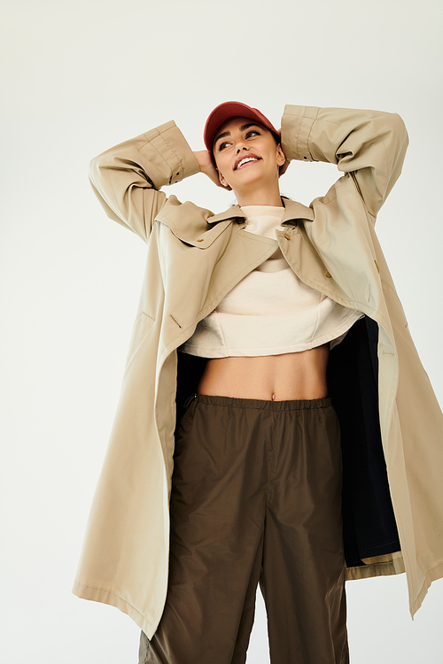 A young woman poses confidently in a chic autumn outfit, showcasing her style in a bright studio setting.