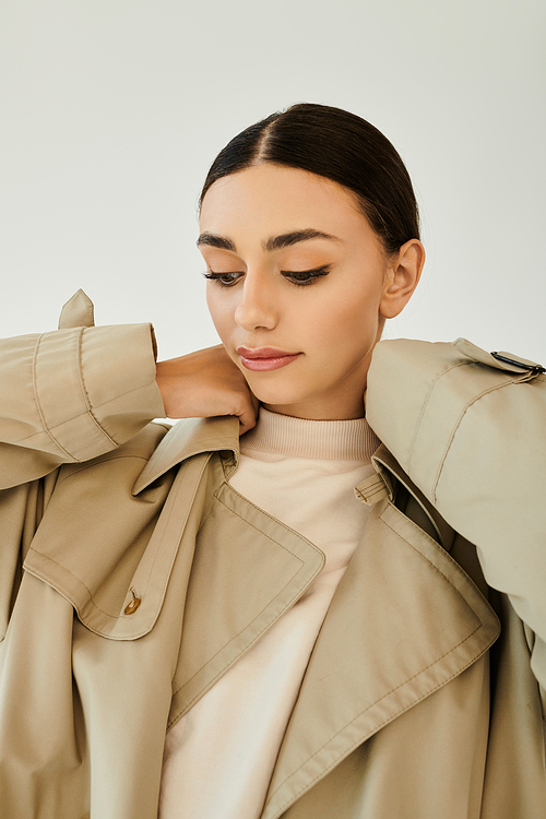 A young woman poses elegantly in a chic autumn outfit, capturing the essence of seasonal fashion in a studio atmosphere.