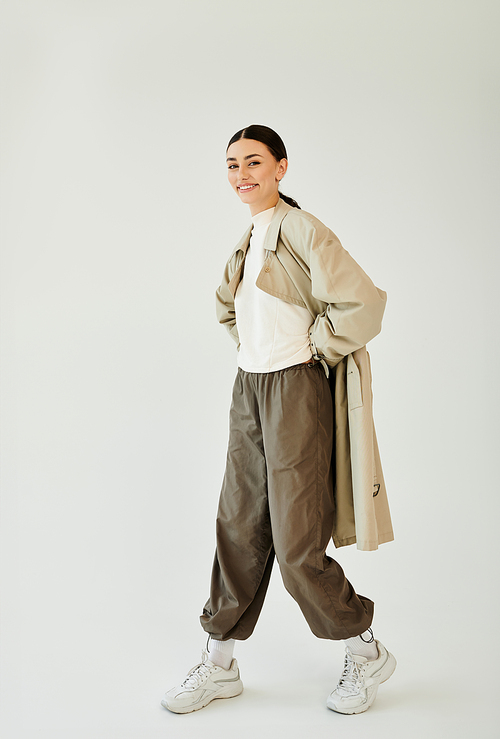 A confident young woman models a trendy autumn outfit, radiating seasonal charm in a cozy studio.