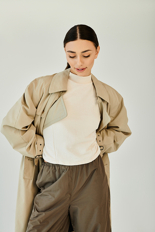 A young woman radiates elegance in a chic autumn outfit, beautifully posing in a minimalist studio setting.