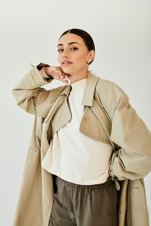 A young woman confidently poses in a chic autumn outfit, embracing seasonal style in a contemporary studio.