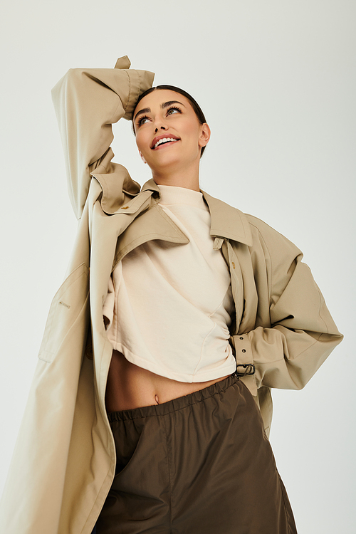 A young woman poses gracefully in a fashionable autumn outfit, radiating confidence in a well-lit studio space.