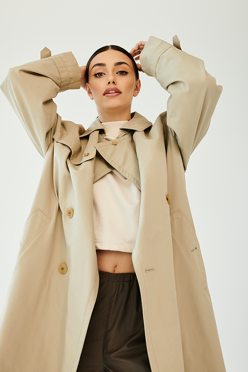 A young woman poses confidently in an autumn outfit, radiating style and elegance within a contemporary studio backdrop.